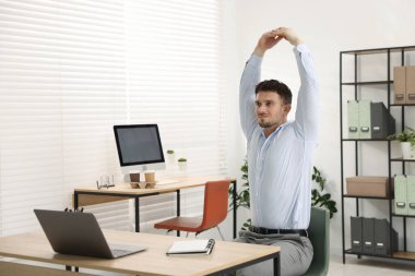 Ofiste sandalyeye uzanan yakışıklı adam.