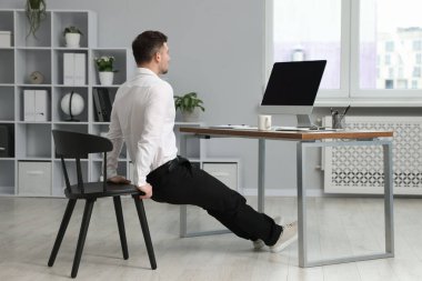 Adam ofiste sandalye ile egzersiz yapıyor