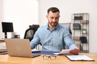 Ofiste masa başında çalışan yakışıklı adam.