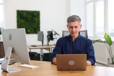 Ofiste masada dizüstü bilgisayar üzerinde çalışan işadamı