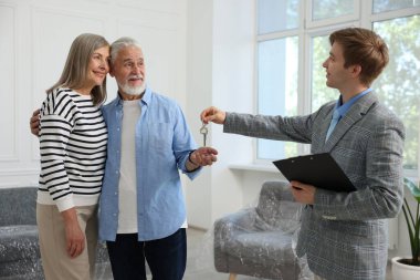 Gülümseyen emlakçı evin anahtarını evdeki yeni sahibine veriyor.