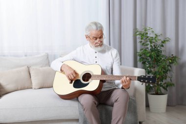 Rahatlatıcı hobi. Son sınıf öğrencisi evdeki kanepede gitar çalıyor.