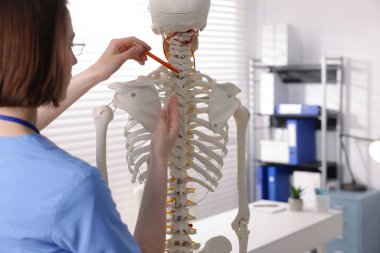 Doktor klinikteki insan iskeleti parçalarına işaret ediyor.