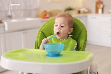 Küçük şirin bebek, yüksek sandalyede sağlıklı yiyecekler yiyor.