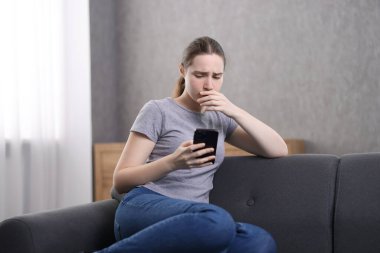Depresyondaki kadın evdeki kanepede ruh sağlığı için yardım hattını arıyor.