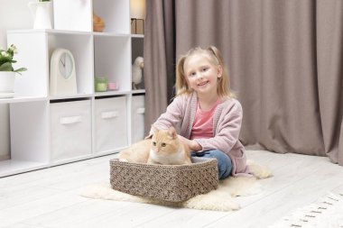 Evde kızıl kedisi olan küçük bir kız.