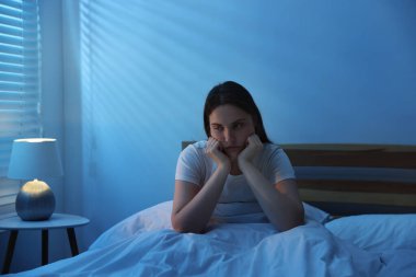 Yatakta uykusuzluk çeken sinirli genç bir kadın.