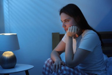 Yatakta uykusuzluk çeken sinirli genç bir kadın.