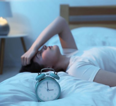 Evde yatakta uykusuzluk çeken sinirli genç kadın, alarma odaklan.