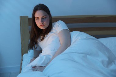 Yatakta uykusuzluk çeken sinirli genç bir kadın.