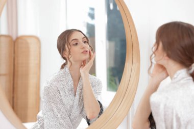 Güzel bir kadın aynada kendine bakıyor.