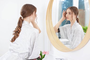 Güzel bir kadın aynada kendine bakıyor.