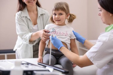 Sonograf, kızın kalbinin ultrason muayenesini yapıyor. Anne ve kızının klinikte doktorla randevusu var.