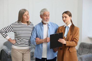 Evdeki çiftle çalışan panolu bir emlakçı.