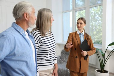 Gülümseyen bir emlakçı pano ile evde çiftlerle çalışıyor.