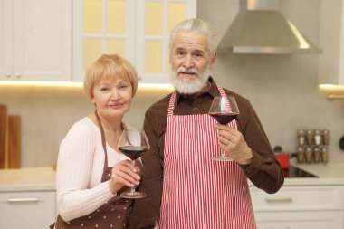 Mutfakta şarap bardakları olan yaşlı bir çift.