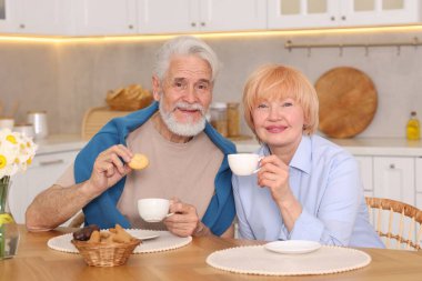 Mutfaktaki ahşap masada birlikte kahvaltı eden sevimli yaşlı çift.
