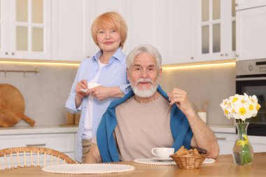 Mutfaktaki ahşap masada birlikte kahvaltı eden sevimli yaşlı çift.