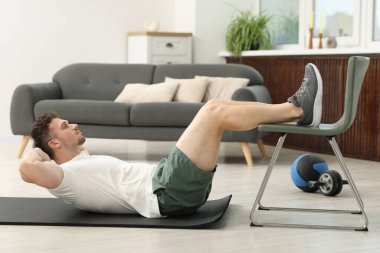 Evde sandalyeyle egzersiz yapan yakışıklı adam.