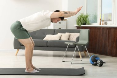 Evde spor paspası üzerinde egzersiz yapan yakışıklı bir adam.