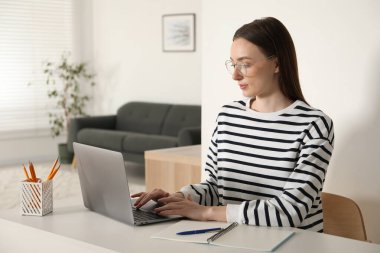 İçerideki masada dizüstü bilgisayar kullanan bir kadın. Kendi kendine çalışma.