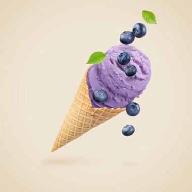 Lezzetli yaban mersinli dondurma ve gri arka planda havada böğürtlenler.