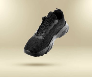 Havada bej renkli arka planda moda siyah spor ayakkabısı