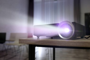 Modern video projektörü içeride ahşap masa üzerinde çalışıyor.