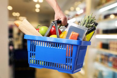 Süpermarkette elinde farklı gıda ürünleri olan bir adam var.