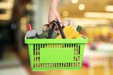 Süpermarkette elinde farklı gıda ürünleri olan bir adam var.