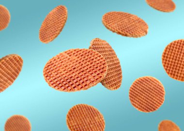 Açık mavi gradyan üzerinde uçan lezzetli Hollanda waffleları (stroopwafels)