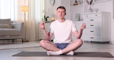 Genç adam evde yoga yapıyor.