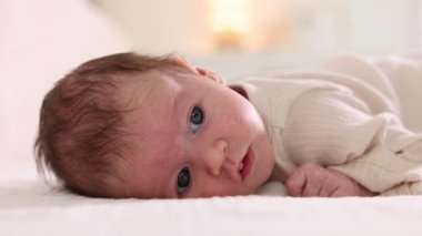 Sevimli yeni doğmuş bebek yatakta uzanıyor, yakın plan.