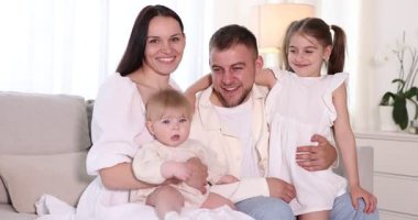 Mutlu ebeveynler ve çocukları evdeki kanepede birlikte.