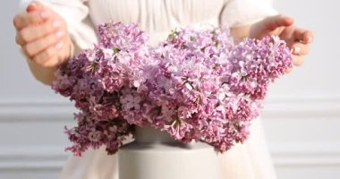 Kapalı alanda güzel leylak çiçekleri olan kadın, yakın plan.