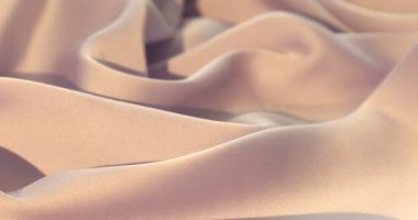 Arka plan olarak buruşuk bej ipek kumaş, yakın plan. Kamera sola hareket ediyor