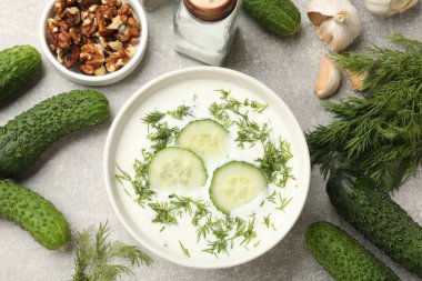 Lezzetli salatalık çorbası, dereotlu kase ve gri dokuma sehpada ürünler.