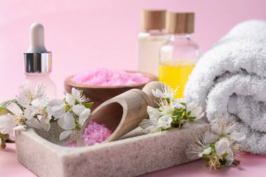 Kozmetik ürünleriyle kaplıca kompozisyonu ve pembe arka planda güzel çiçekler, yakın plan.