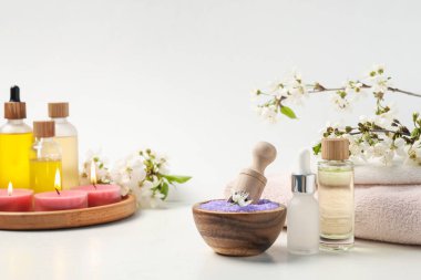 Spa ürünleri, güzel çiçekler ve beyaz masada yanan mumlar, yakın plan.