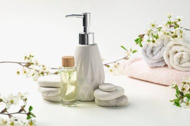 Spa ürünleri, çakıl taşları ve beyaz masadaki güzel çiçekli dallar, yakın plan.