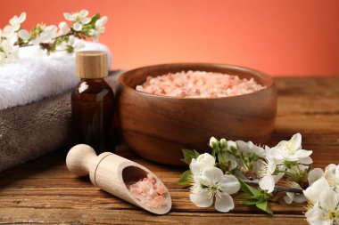 Deniz tuzu, kozmetik ürünleri ve ahşap masa üzerindeki güzel çiçeklerle kaplıca kompozisyonu.