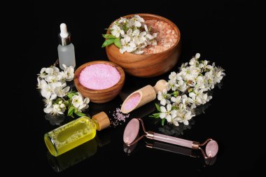 Siyah ayna yüzeyinde kozmetik ürünleri ve güzel çiçeklerle spa kompozisyonu