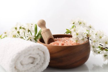 Spa mı? Deniz tuzu, havlu ve beyaz arka planda güzel çiçekler, yakın plan.