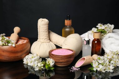 Siyah ayna yüzeyinde kozmetik ürünleri ve güzel çiçeklerle kaplıca kompozisyonu, yakın plan.