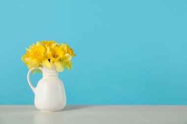 Masadaki vazodaki nergisler açık mavi arka planda. Metin için boşluk