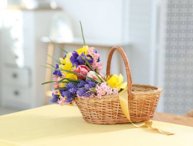 İçerideki masada güzel çiçekler olan hasır sepet.