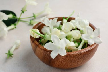 Bej masanın üzerinde yasemin çiçekleri olan kase, yakın plan.