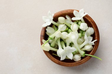 Üzerinde yasemin çiçekleri olan bir kase bej masa, üst manzara. Metin için boşluk