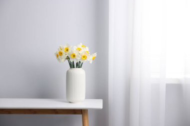 Beyaz masadaki vazodaki güzel nergisler, metin için yer.