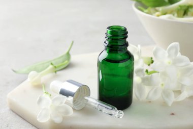 Yağ şişesi ve yasemin çiçekleri masada, yakın plan.